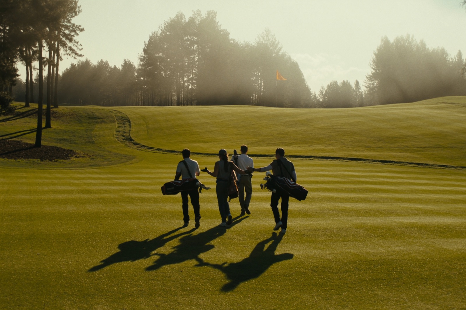 Four golfers walking the fairway at sunrise